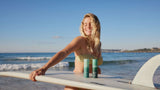 Woman at the beach with surfboard and SAMI skincare cleansers for glowing skin and effortless outdoor beauty routines