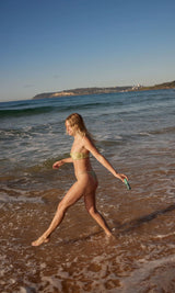 Woman walking along the beach holding SAMI skincare cleanser inspired by effortless outdoor beauty and healthy glowing skin